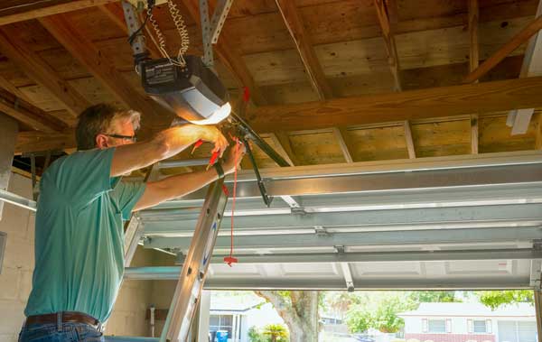 Handy man performing garage door repair as part of Zenith's property management maintenance contract