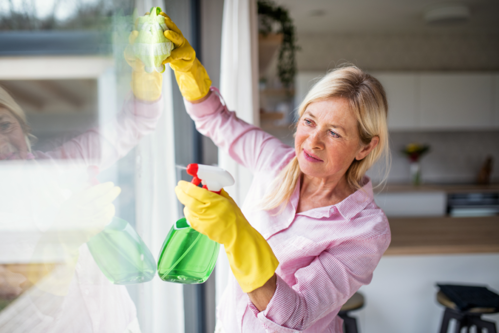 Woman cleaning windows. Zenith Properties NW in Clark County WA offers some helpful summer home maintenance tips.