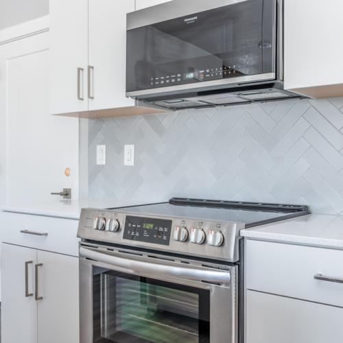 Closer look of stove, over-the-range microwave, and cabinets at Grove 162nd.