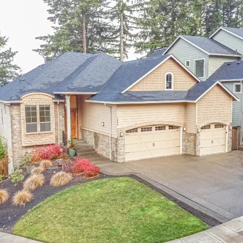 Exterior of a spacious, multi-level rental home featuring stone accents, a landscaped front yard, and a wide driveway, professionally overseen by Zenith Properties NW in Mill Plain